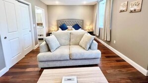 Ein modernes Wohnzimmer mit einer grauen Eckcouch, einem weißen Couchtisch und einem großen Fenster mit Vorhängen.