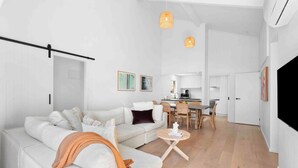 Un salon moderne comprenant un canapé, une table basse et un coin repas avec des chaises et une table.