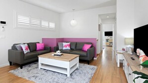 A modern living room with two grey sofas, a white coffee table, and a pink accent wall. - Kismet- Family fav, 12pm check out, Parking, Walk to the beach (Ocean Grove)