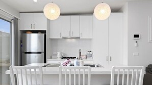 A modern kitchen with white cabinets, a stainless steel refrigerator, a gas stove, and two pendant lights. - Kismet- Family fav, 12pm check out, Parking, Walk to the beach (Ocean Grove)