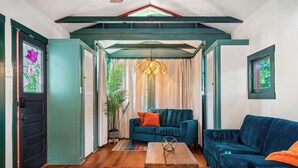 A cozy living room with a teal sofa, a wooden coffee table, and a large window.