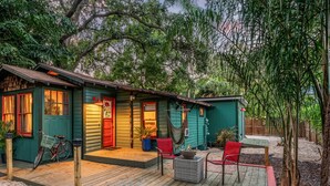 A small, two-story house with a porch, a fire pit, and a hammock.