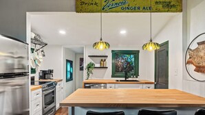 A modern kitchen with a wooden island, stainless steel appliances, and hanging pendant lights.