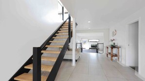 A modern interior with a staircase, a kitchen area, and a hallway leading to a living space. - Ocean Escape- 5 Bedroom, 3 bath- Sleeps 11, beach (Ocean Grove)