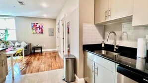 A modern kitchen with stainless steel appliances, a black countertop, and white cabinets.