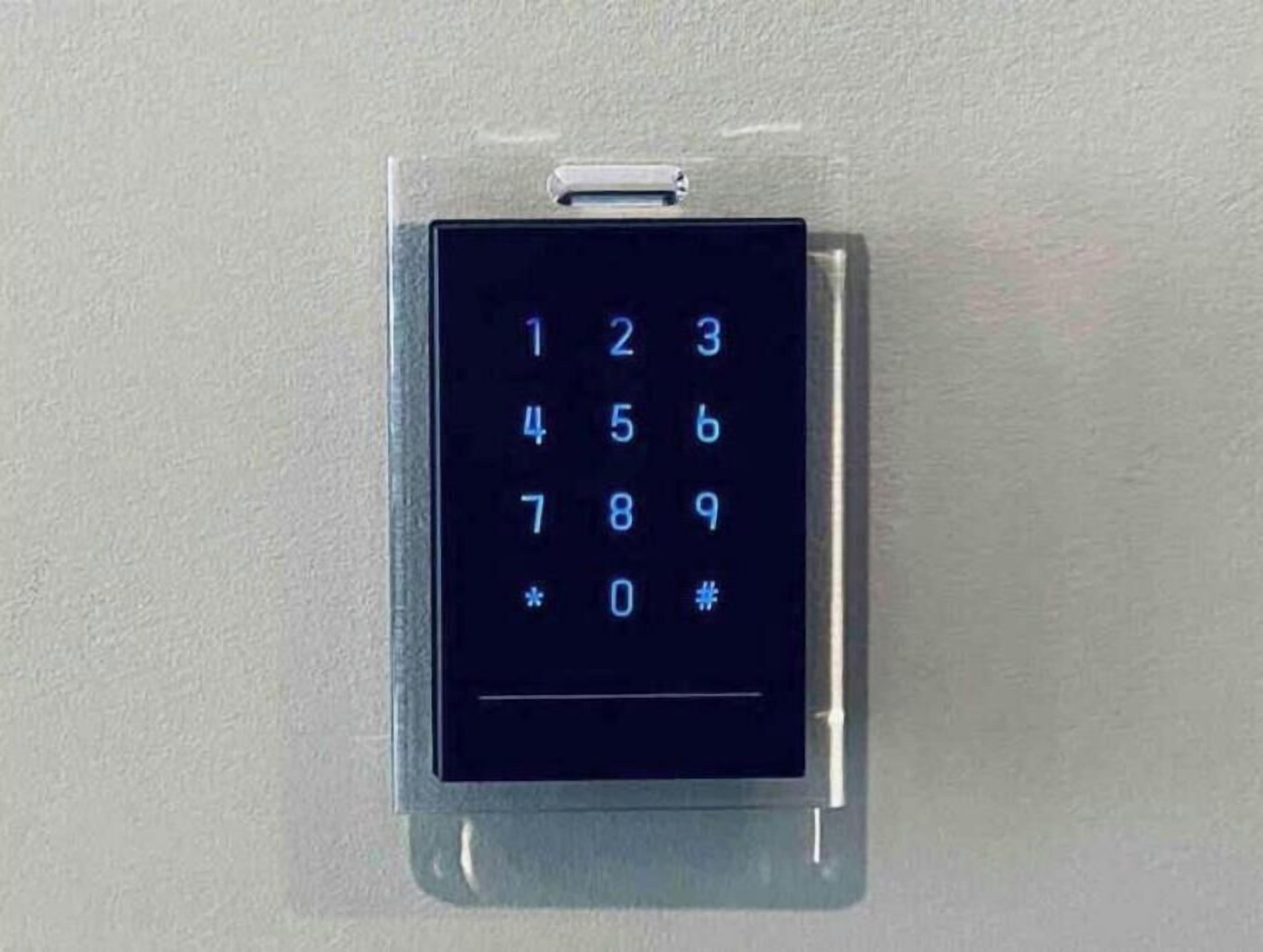 Um painel de teclado fixado na parede, provavelmente para uma porta ou controle de acesso.