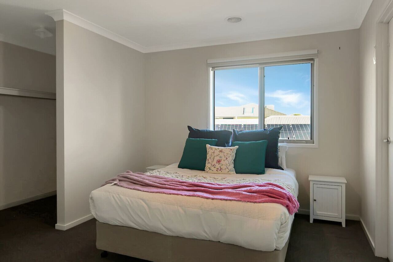 Een slaapkamer met een bed, een raam, een nachtkastje en een garderobe.