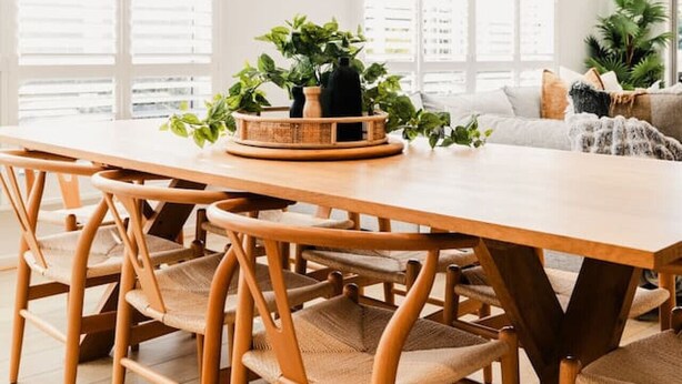 A modern dining area with a wooden table and chairs, two hanging pendant lights, and a potted plant on the table. - Hamptons Haven; Luxe 4 bedroom, 2 bathroom, WIFI (Armstrong Creek)