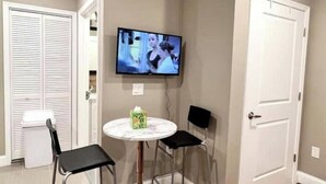 A small room with a television mounted on the wall, a round table with two chairs, a trash bin, and a door. - 406 The easy stays in central city of Philadelphia (Philadelphia)