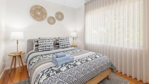 A bedroom with a bed, two bedside tables, a ceiling fan, and a window with sheer curtains. - The Shack- Fireplace, walk to beach, pet friendly (Saint Leonards)