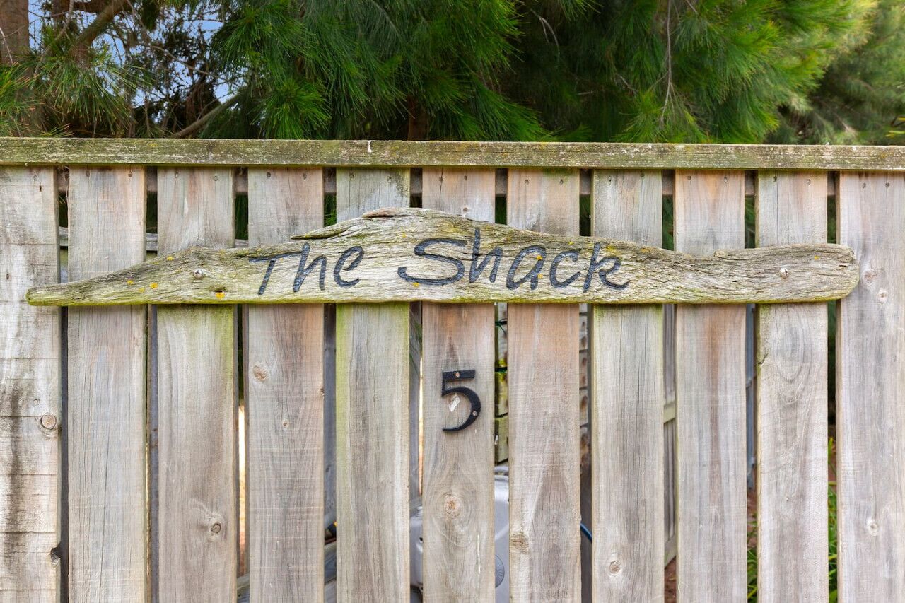 Een houten hek met een bord waarop 'The Shack' en het nummer 5 staat.