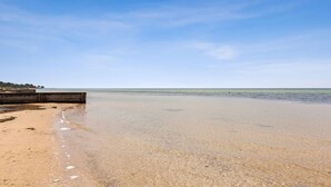 A beach with clear skies, calm water, and a wooden structure on the left. - The Shack- Fireplace, walk to beach, pet friendly (Saint Leonards)