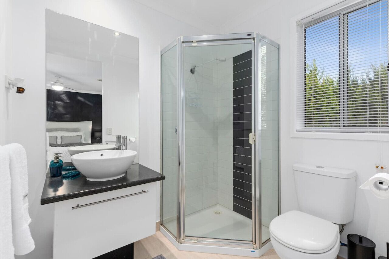 Une salle de bain moderne avec une douche à parois de verre, un lavabo blanc et des toilettes.
