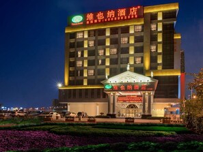 Un hôtel doté d’une entrée imposante, d’une grande enseigne avec des caractères chinois et d’une façade bien éclairée.
