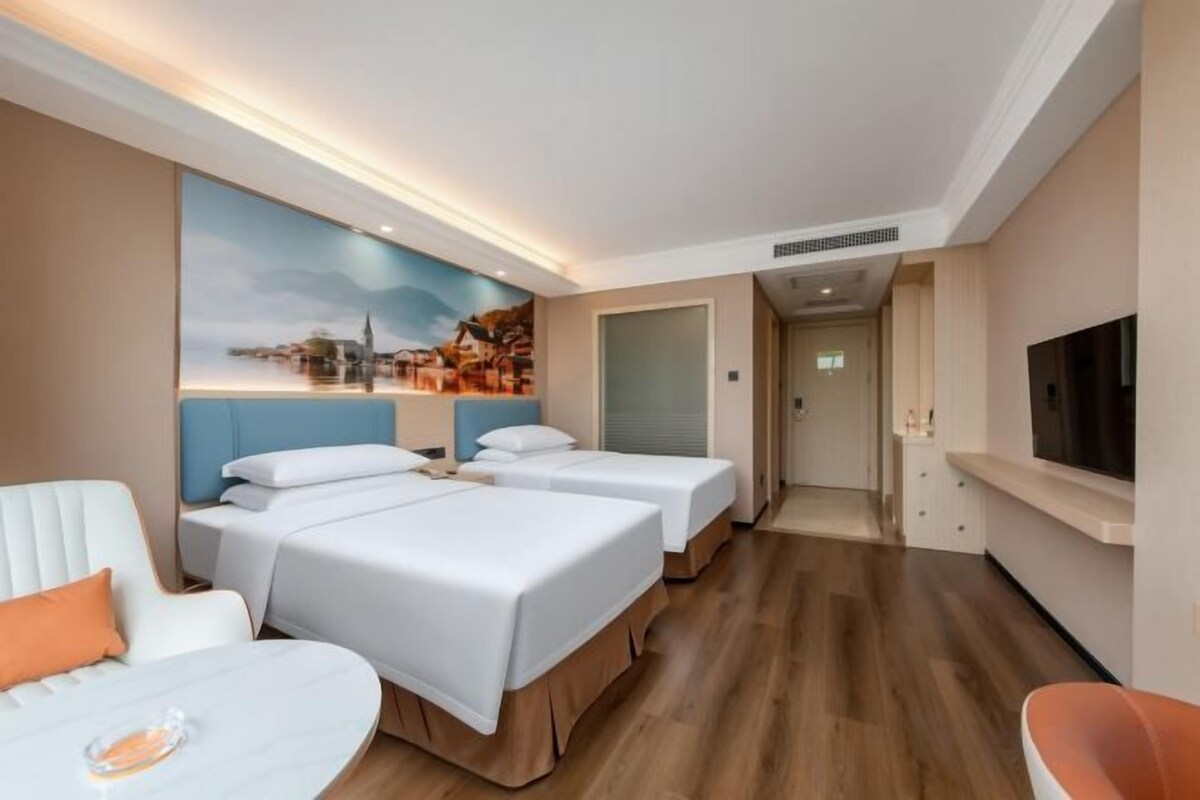 A hotel room with two beds, a TV, a seating area, and a painting on the wall.