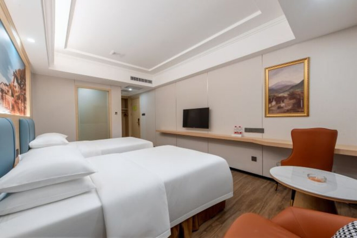 A hotel room with two beds, a TV, a desk, and a chair.