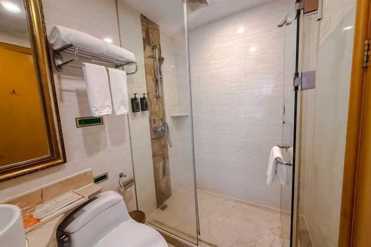 A modern bathroom with a glass-enclosed shower, a vanity with a mirror, and a towel rack.