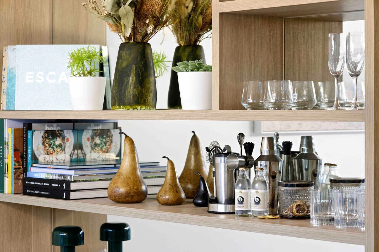 A shelf with books, decorative vases, and kitchenware.