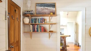 A room with a leather chair, wooden shelves with books, a painting, and a wooden door.