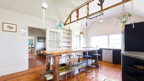 A rustic kitchen with wooden floors, a wooden bar counter, and hanging plants.