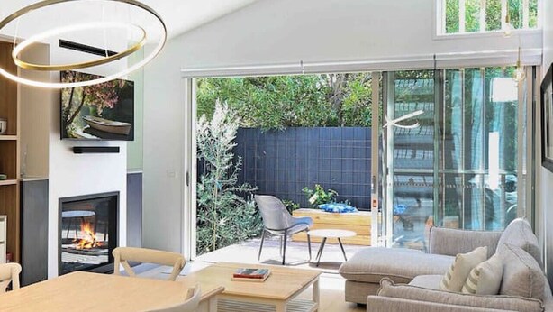 A modern living room with a fireplace, a dining area, and a seating area with a sofa and chairs. - Beach luxury retreat- 2 bedroom, 2 bathroom, shops (Ocean Grove)