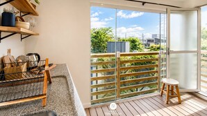 Une cuisine moderne avec un plan de travail en bois, une plante suspendue et une vue sur la ville grâce à de grandes fenêtres.