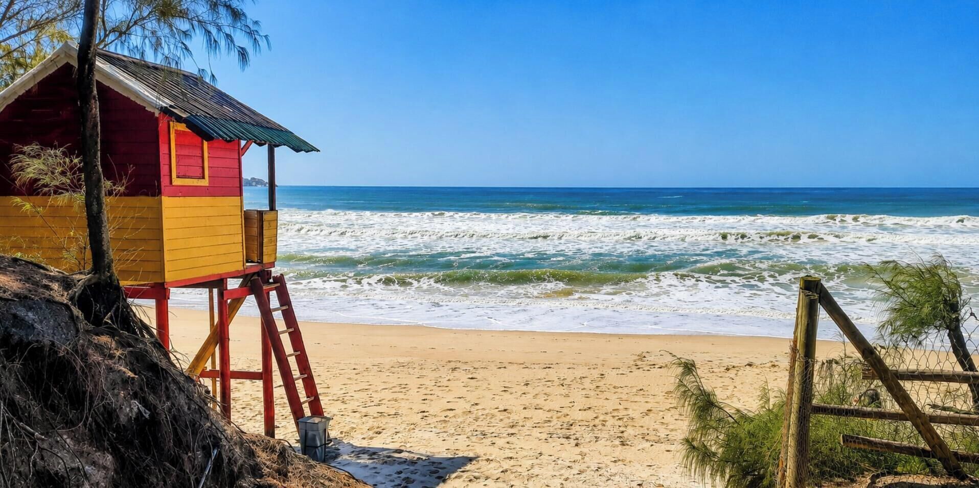 A lifeguard tower on a beach with waves in the background.
