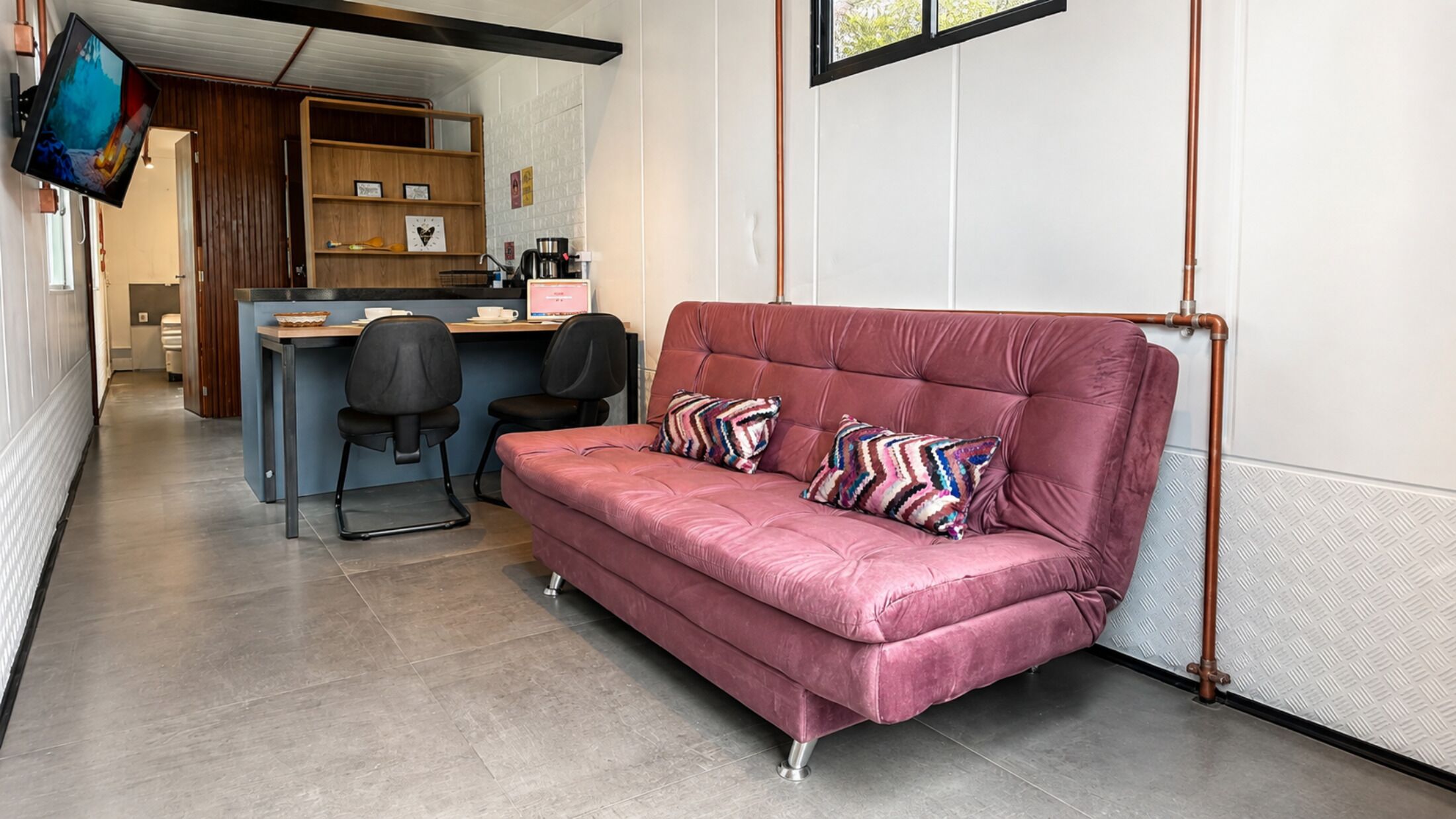 Een moderne woonruimte met een bank, bureau en televisie.