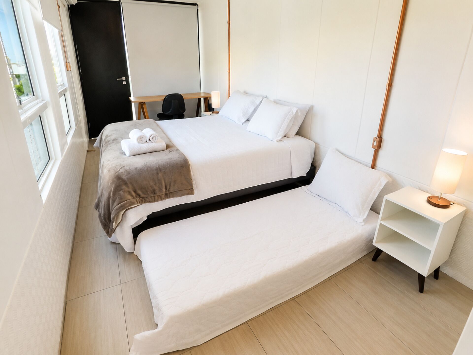 Une chambre d’hôtel avec un lit, une table de chevet, une lampe et une vue sur l’extérieur.