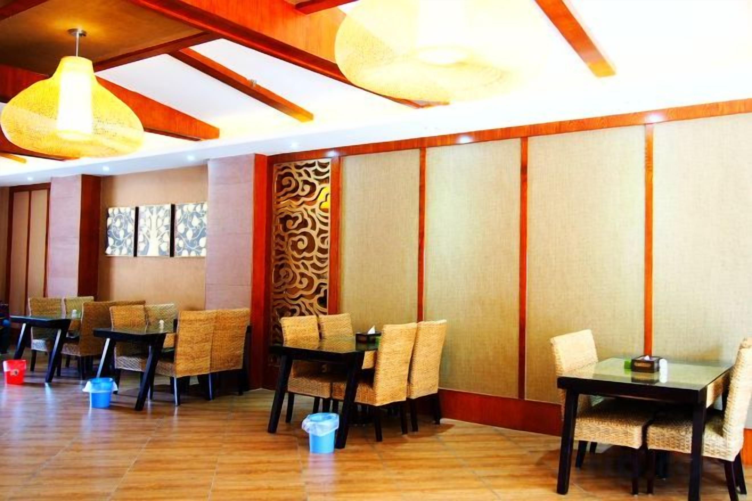 A restaurant with wooden flooring, tables with chairs, and hanging light fixtures.