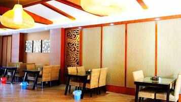 A restaurant with wooden flooring, tables with chairs, and hanging light fixtures.
