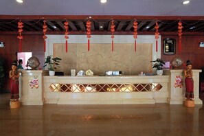A reception desk with a decorative backdrop, a clock, and a plant. - Mengla Zai Ya Ge Ha Hotel (Mengla)