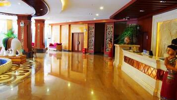 A hotel lobby with a reception desk, seating area, and decorative elements.