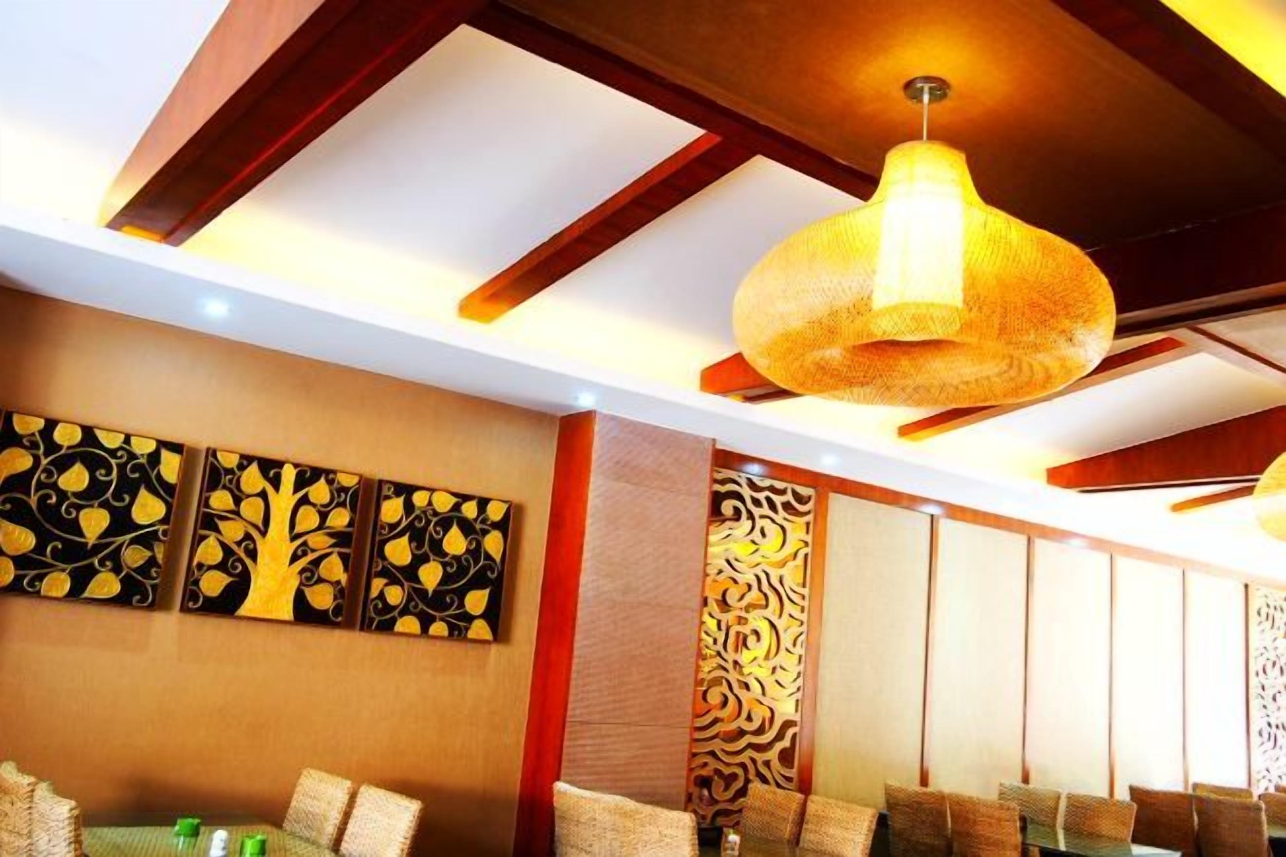 A dining area with a high ceiling, decorative wall panels, and a hanging light fixture.
