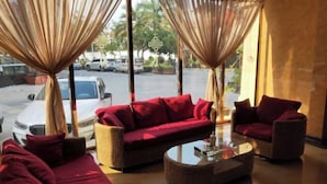 A room with a red sofa, a wicker armchair, and a glass coffee table.