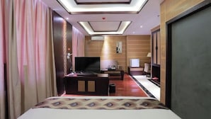 A hotel room with a bed, a TV, a desk, and a seating area with a sofa and chairs.