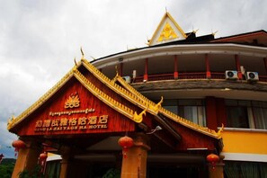 A hotel with a traditional architectural style, featuring a prominent entrance with a red facade and golden accents. - Mengla Zai Ya Ge Ha Hotel (Mengla)