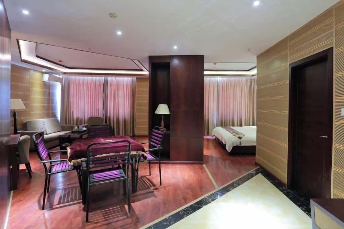 A hotel room with a sofa, chairs, a bed, a desk, and a lamp.