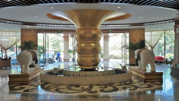 A lobby with a central fountain, large columns, and decorative statues.