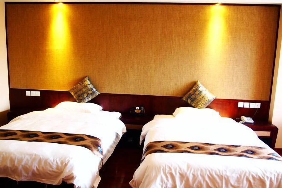 A hotel room with two single beds, each with a patterned bedspread and matching pillows.