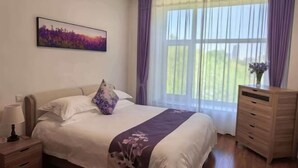 A bedroom with a bed, a nightstand, a dresser, a window with curtains, and a painting on the wall. - Changchun Nanhu Hotel Qingyue Villa Holiday Apartment (Changchun)