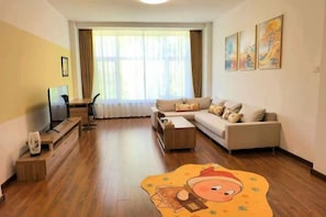 A living room with a sofa, a coffee table, a TV, and a window with curtains. - Changchun Nanhu Hotel Qingyue Villa Holiday Apartment (Changchun)