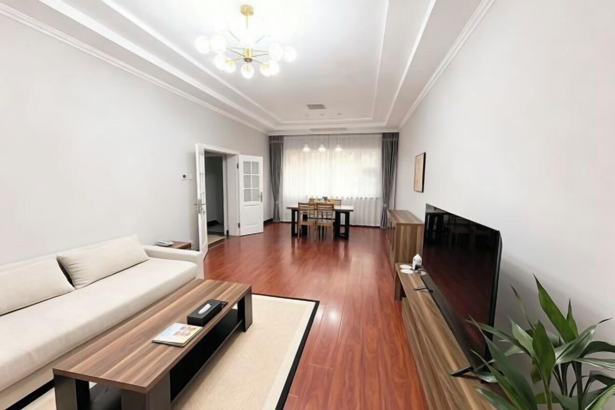 Una sala moderna con sofá, mesa de centro, televisor y comedor.
