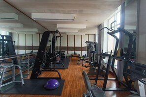 Ett gym med träningsutrustning, en vägg med speglar och ett trägolv.
