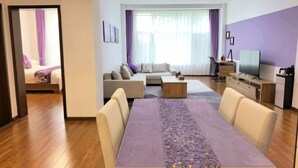 A modern living room with a dining table, sofas, a TV, and a kitchen area. - Changchun Nanhu Hotel Qingyue Villa Holiday Apartment (Changchun)