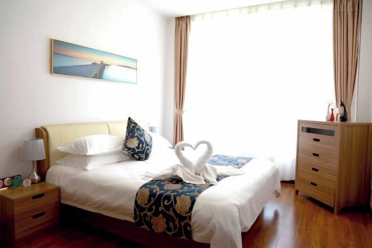 Quarto de hotel com cama, mesa de cabeceira, cômoda e um quadro na parede.