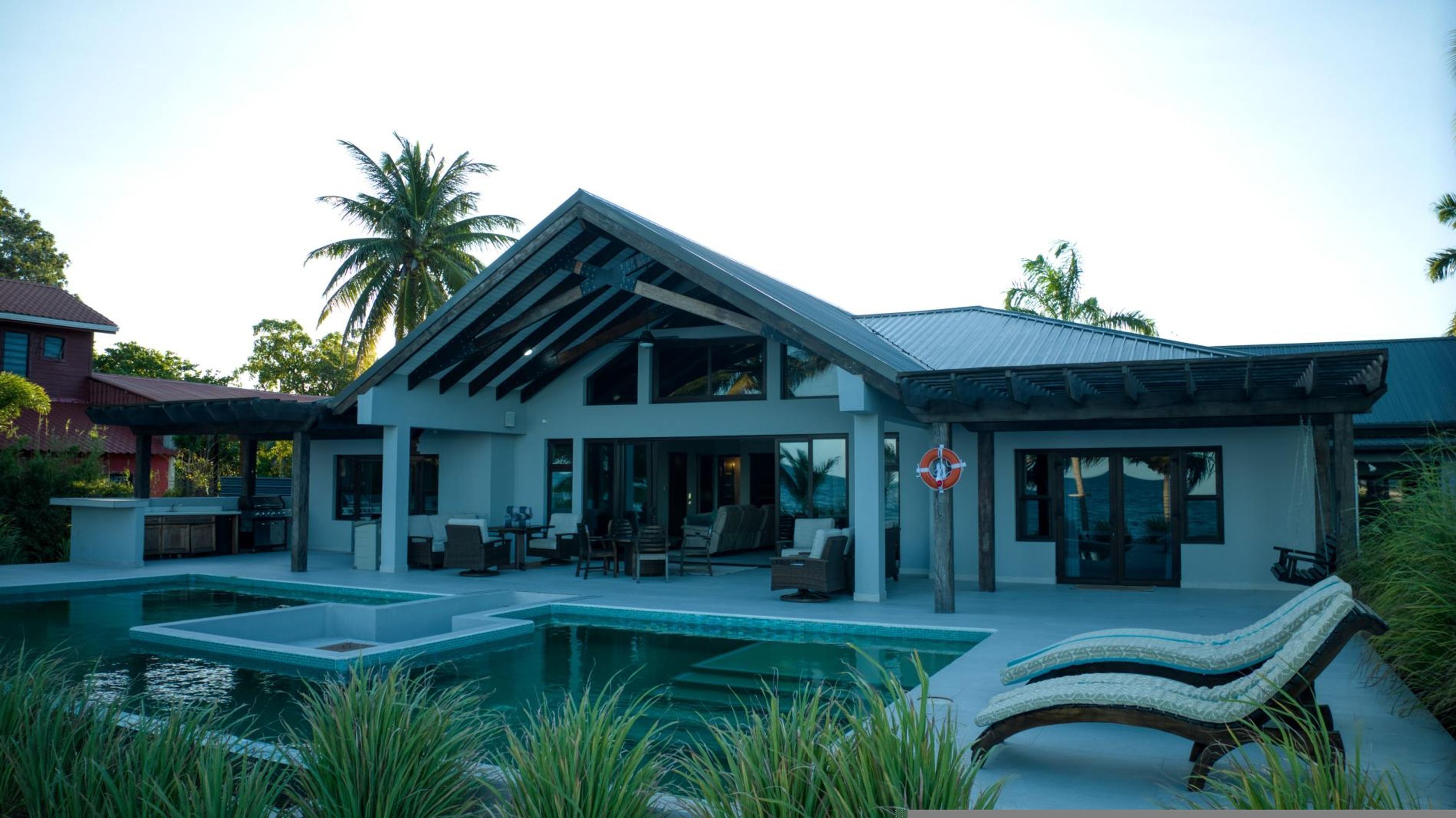 A modern house with a pool, outdoor seating, and a lifebuoy.