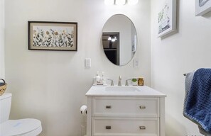 A bathroom with a white sink, mirror, and framed artwork on the wall. - Rustic Lakehouse kayaks fishing bonfires (Inverness)