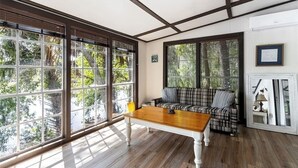 A room with large windows, a wooden table, a plaid sofa, and a white cabinet. - Rustic Lakehouse kayaks fishing bonfires (Inverness)