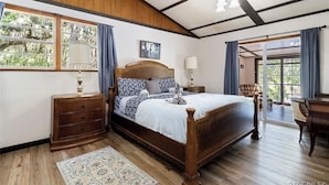 A bedroom with a wooden bed, a nightstand, a dresser, a large window with curtains, and a view of the outdoors. - Rustic Lakehouse kayaks fishing bonfires (Inverness)